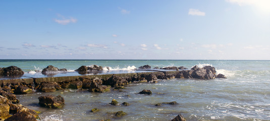 Fototapeta na wymiar Sea pier with rocks under the sun