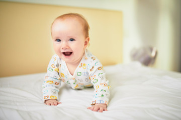 Adorable baby girl in pyjamas having fun in nursery