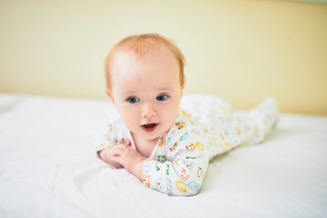 Adorable baby girl in pyjamas having fun in nursery