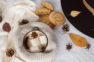 Fototapeta na wymiar Autumn and Winter composition. Hot coffee with marshmallows, scarf, cookies, hat, bumps and autumn leaves. Flat lay, top view