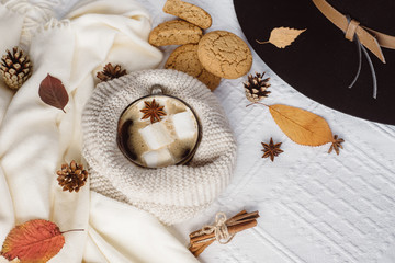 Fototapeta na wymiar Autumn and Winter composition. Hot coffee with marshmallows, scarf, cookies, hat, bumps and autumn leaves. Flat lay, top view
