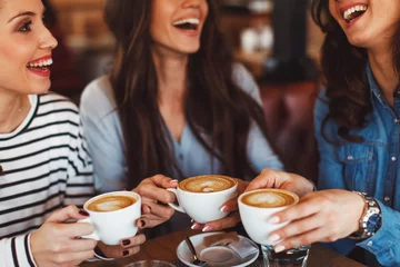 Fototapeten Three young women enjoy coffee at a coffee shop © djile