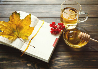 Tea and autumn coziness. A cup of tea, a book, maple leaves create an autumn mood  on a wooden...