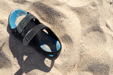 Old sandal on the sand at a beach as background with copy space