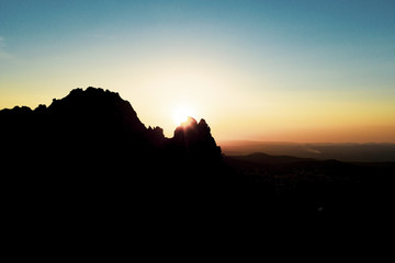 Aerial view of a spectacular sunset behind some rocky mountains in Sardinia, Italy.