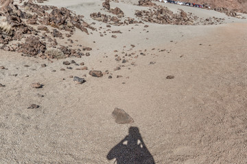 Shadow of a photographer projected on the warm sand of a desert landscape, Canary Islands