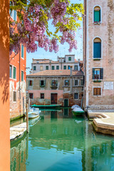 Fototapeta na wymiar Venice, Italy: venetian canal with colorful buildings, flowers and boats