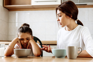 Family. Eating. Education. Mom is talking to her daughter who is refusing to eat; in the kitchen at...