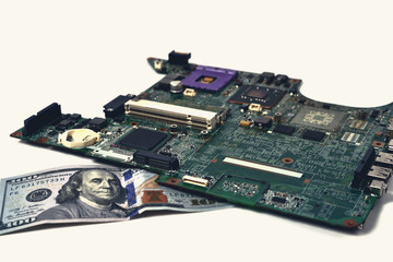 An old chip from a laptop lies on a bill of one hundred dollars, a white background, toning,