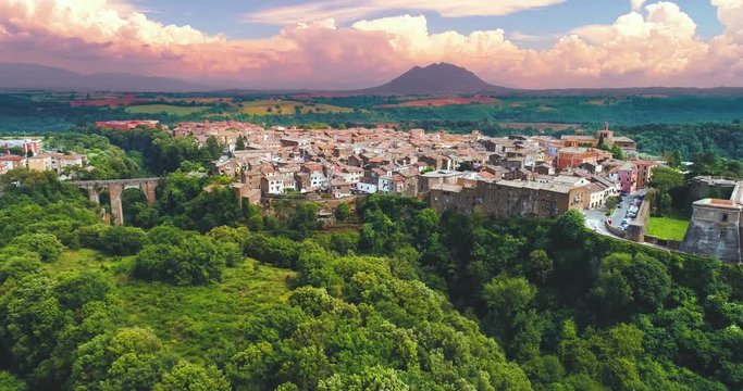 4k An aerial view of the town of Civita Castellana in Italy, pink cloudy sky and green trees and grass