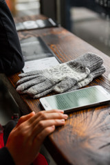 Naklejka premium reading a digital book on a cellphone with a pair of gloves on the table in a coffee shop during winter