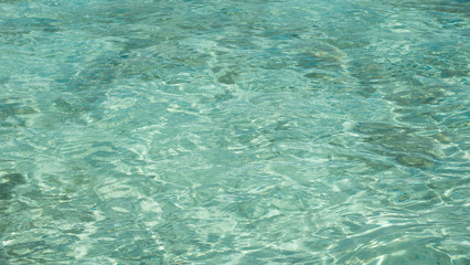 a clear and transparent blue green sea with shallow water and sun reflection