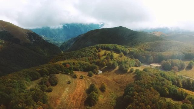 Beautiful autumn season Italian landscapes of hills, mountains and valleys with cattle grazing and trees and foggy clouds, Aerial view
