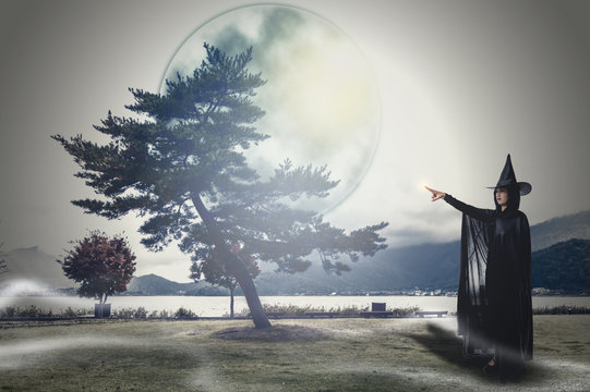 woman in Black Scary witch halloween costume with moonlight in a dark forest