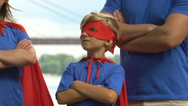Super family crossing hands on chest in superhero pose, parents and kid together