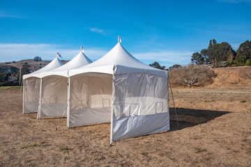 White tent in brown grass field under blue sky © Frank Fennema