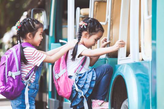 Asian pupil kids with backpack holding hand and going to school with school bus together. Back to school concept.