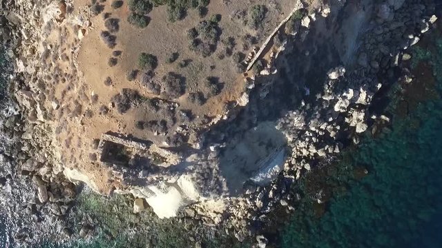 Low drone shot flying close over the ruins of the uninhabited island of Yeronisos Sacred Holy Island off the coast of Cyprus