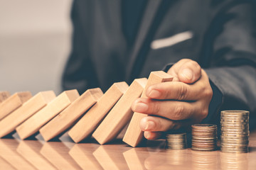 Businessmen use the hands to prevent falling Domino. To maintain the remaining benefits do not fall.