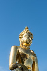 Fototapeta premium From below shot of golden shiny statue of Buddha in sunlight on background of blue sky