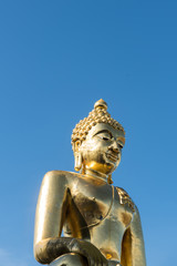 Fototapeta na wymiar From below shot of golden shiny statue of Buddha in sunlight on background of blue sky