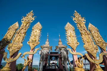 Zelfklevend Fotobehang From below shot of golden ornamental decoration of Golden Triangle area under blue sky, Thailand © Bisual Photo