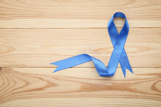 Blue ribbon on brown wooden table. Medicine concept