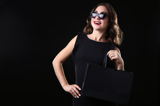 Happy woman with shopping bag on black background