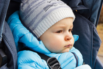 Little child sitting in babies pram, warm clothing for kids concept