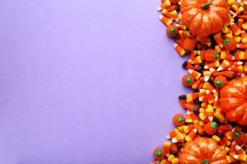 Halloween candy corns and pumpkins on purple background