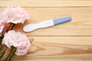 Obraz na płótnie Canvas Pregnancy test with eustoma flowers on wooden table