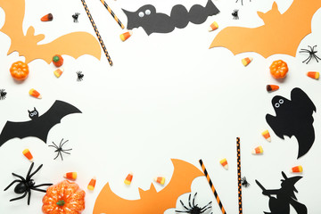 Halloween candies with paper decorations on white wooden table