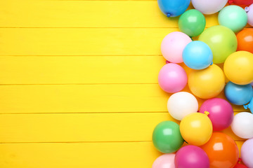 Colorful balloons on yellow wooden table