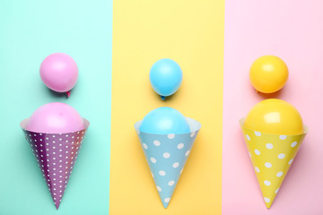 Rubber balloons with birthday paper caps on colorful background