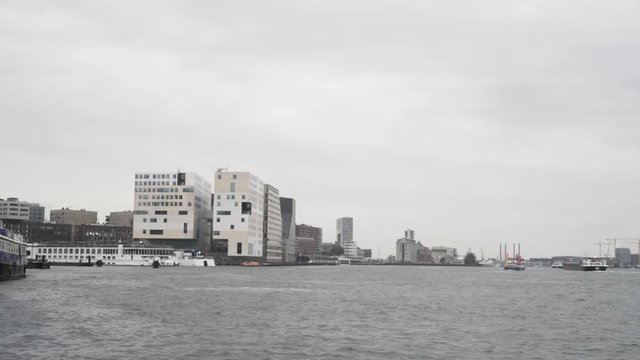A wide shot of the Amsterdam cityscape from t IJ, the famous Dutch river in the middle of the city on an overcast day.