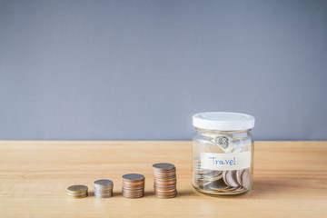 Coin in a glass jar on wooden desk, Saving money for travel concept