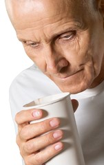 Close-up of senior man in white shirt holding cup isolated on
