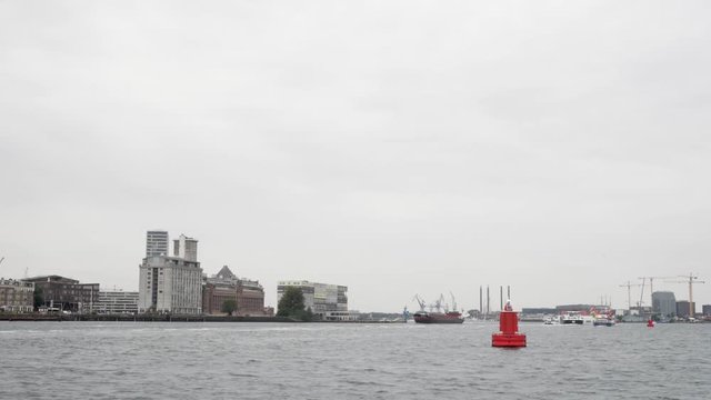 A wide shot of the IJ in Amsterdam on an overcast day, some architectual highlights in the distance.