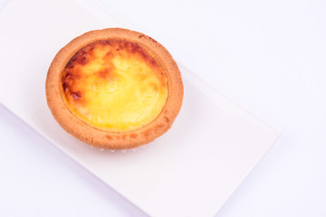A whole cheese tart in a white ceramic plate isolated on white background.
