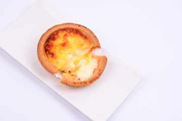 Half eaten cheese tart pastry in a white ceramic plate isolated on white background.