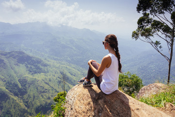 Naklejka na ściany i meble Tracking tourist adventure. Woman sitting on the top of Ella rock, Sri Lanka.