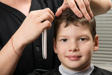 master stylist, makes the boy a straight part in his hair, a dangerous blade