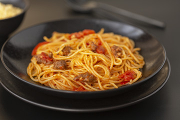 Delicious spaghetti with Bolognese sauce served on a black plate