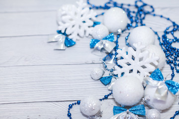 Christmas or new year composition in silver white and blue colors with balls snowflake bows and beads on white wood