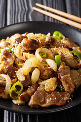Dak-ttongjip is a Korean dish made by stir-frying chicken gizzard with spices close-up on a plate. vertical