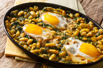 Tasty Iranian dish stew of beans and dill with fried eggs, garlic, turmeric close-up on a table. horizontal