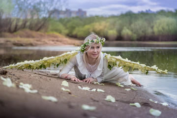 Nice blonde girl with white flower wings near river