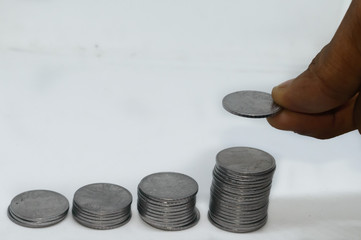 Putting a coin over a stack of coins. Isolated on white background. Concept of money management