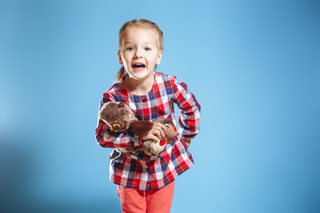 Portrait of cute little girl with toys on blue background.