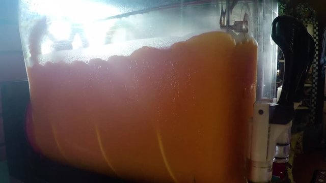 SLOW MOTION - Slurpee Machine with orange slushie in a art store.